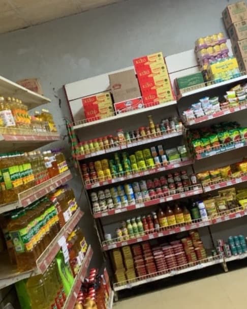 Stocked shelves of cooking oil and provisions in a supermarket aisle